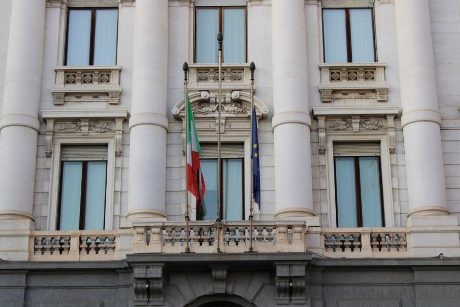 Elegant building facade with Italian and European Union flags in Milan, Italy.